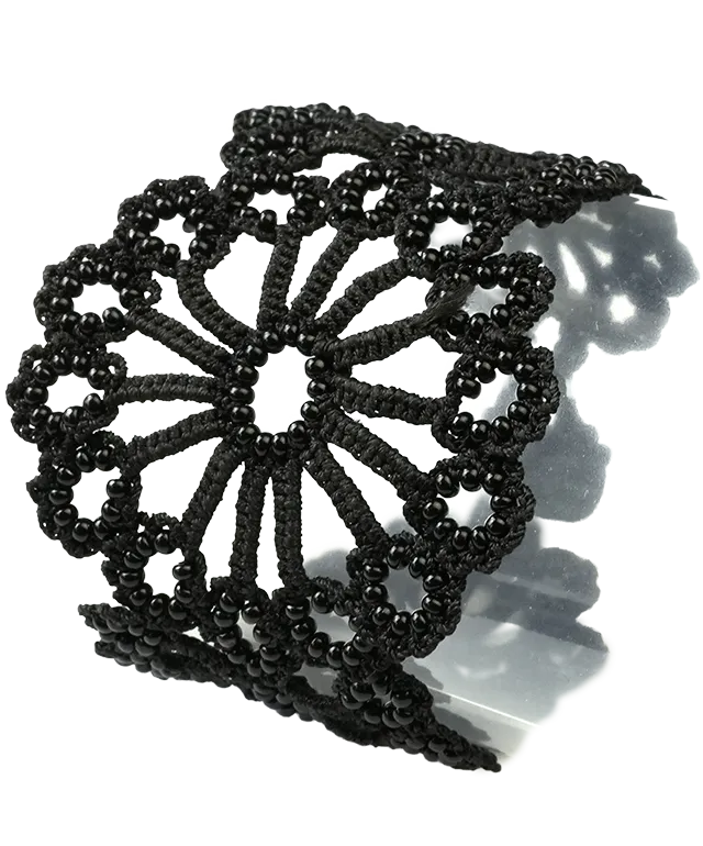 View of the patterns on the Hawa bracelet, handmade in Turkish lace, placed on a pebble