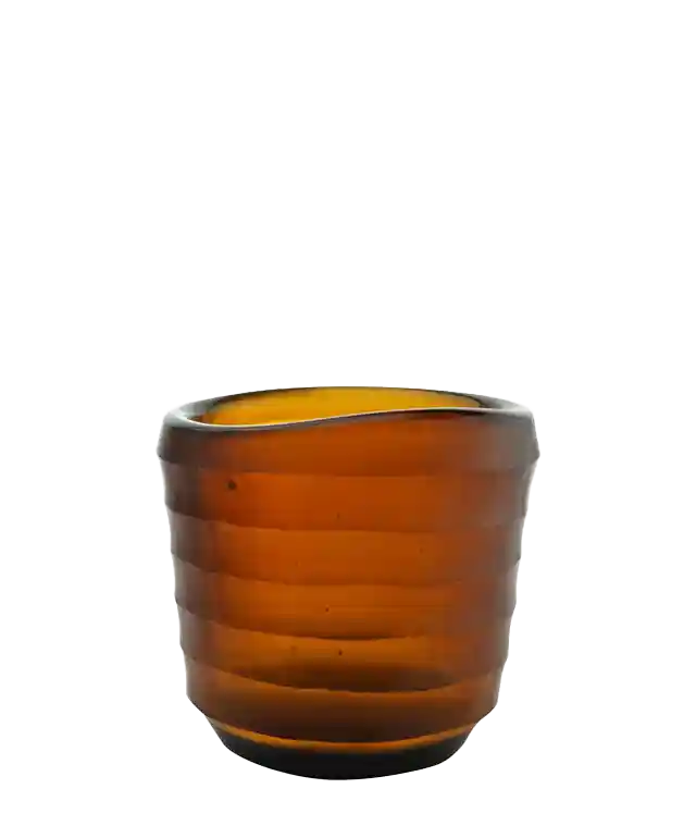 Photophore en verre soufflé coloris Ambre sur une table à dîner, fenêtre en arrière-plan, ambiance de soirée