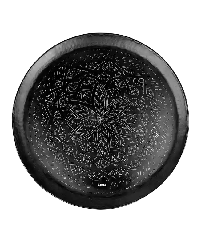 Zoom sur les finitions gravées d'un grand plateau noir en laiton Arabesk, sol en bois