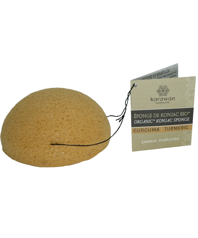 Éponge de konjac avec cordelette et étiquette carton affichant le logo Karawan posée sur une coupelle