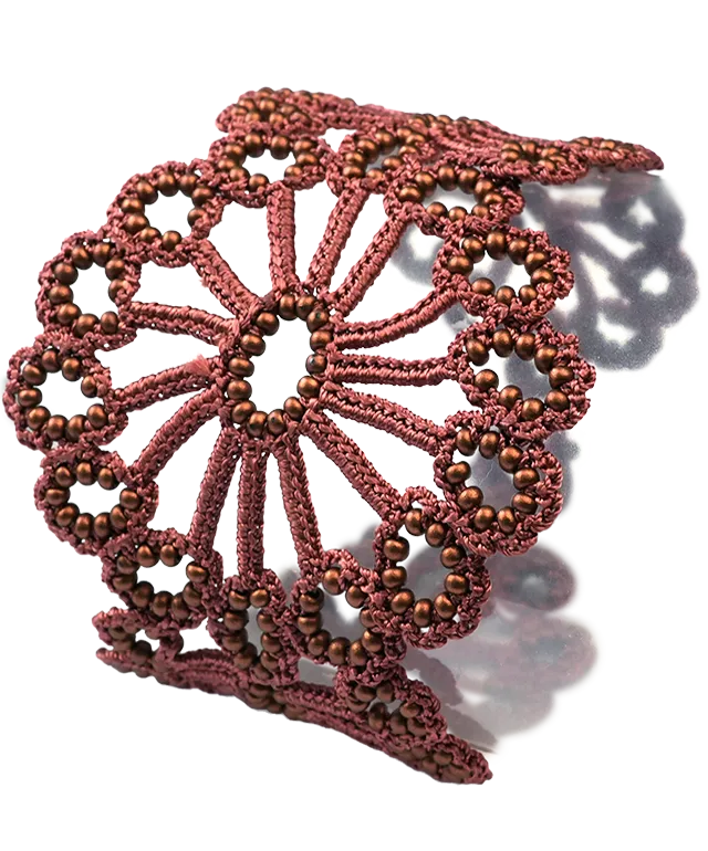 Close-up view of the Matt copper Hawa lace bracelet placed on a white pebble