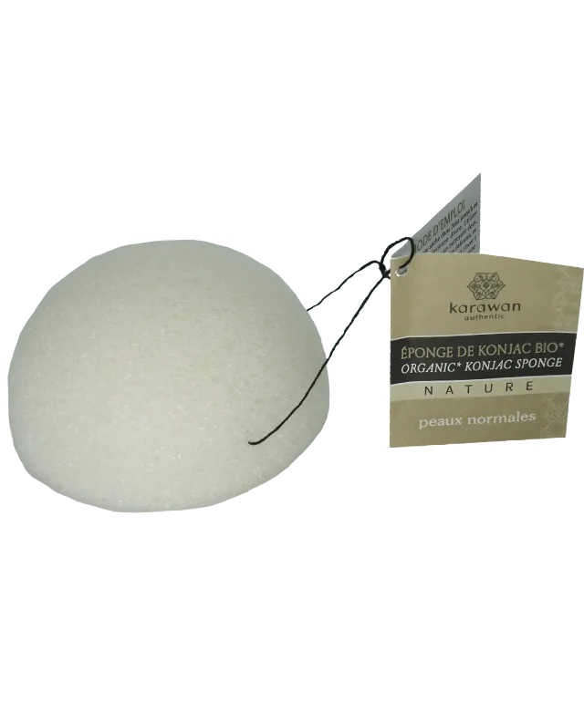 Éponge végétale de konjac naturelle au centre d'une coupelle, posée sur une fouta en coton bio