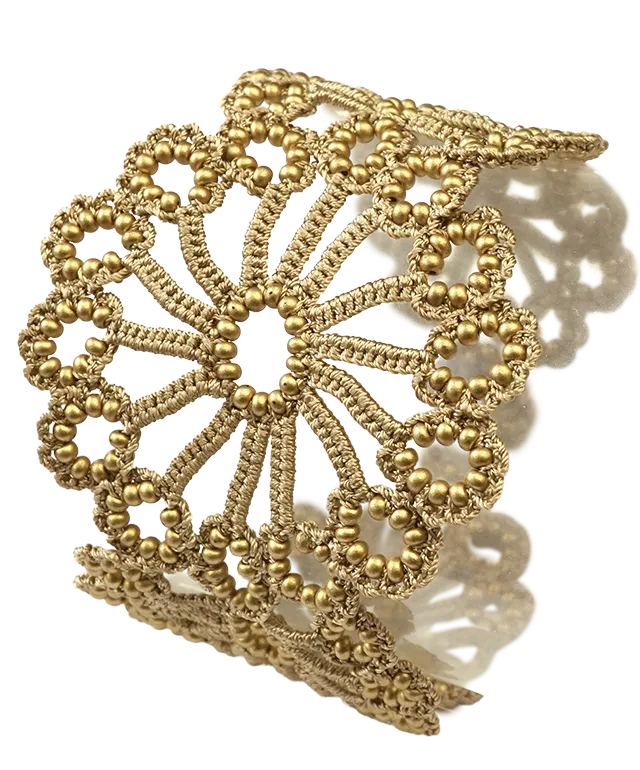 Hawa lace bracelet in matt gold, decorated with pearls, set against a white background
