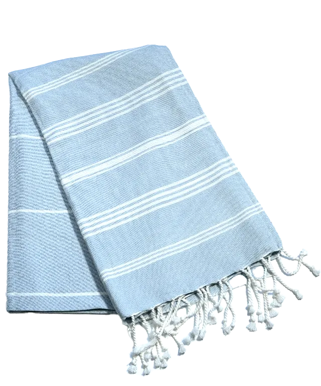 Fouta en coton biologique coloris nuage, accrochée à une échelle en bois, avec une plante verte au premier plan