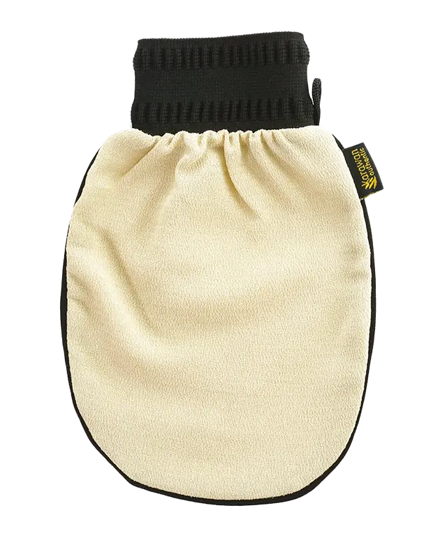 Gant de gommage kessa, beige et noir, posé sur un rebord