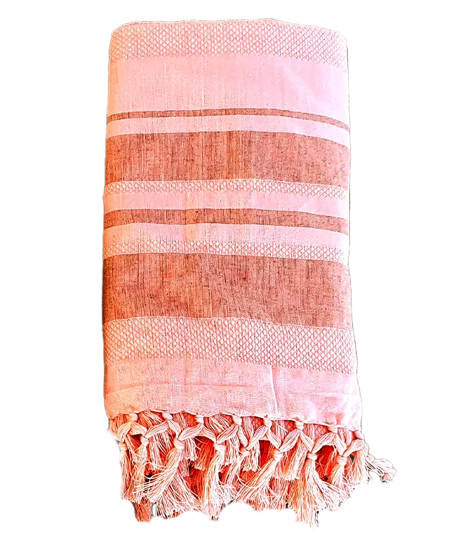 Coral-coloured fouta in organic cotton with honeycomb weave against wooden ladder, stone wall
