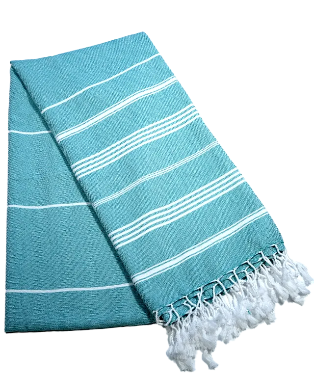 Fouta hammam coloris bleu atoll, posé sur une coupelle en laiton noir, et plante en décoration