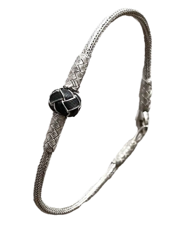 Bracelet en argent de la collection de bijoux Kokaz doté d'un noeud noir, porté par une personne