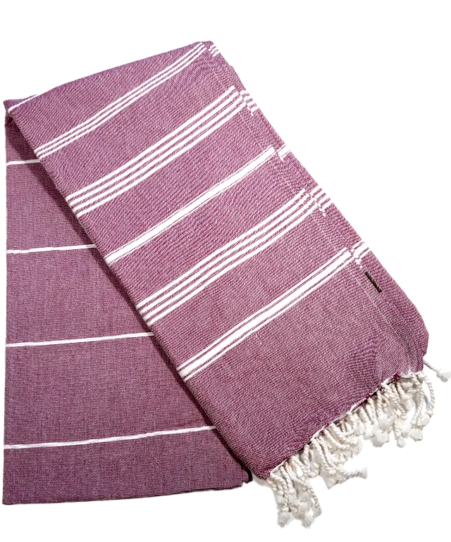 Fouta en coton bio bordeaux, tissée sur chaîne blanche, suspendue à un mur à côté d'une coupelle en laiton