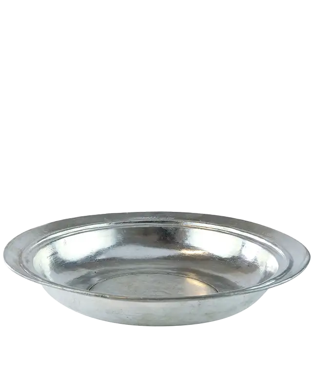 Assiette creuse ancienne en cuivre étamé, posée sur un tissu texturé de couleur foncée