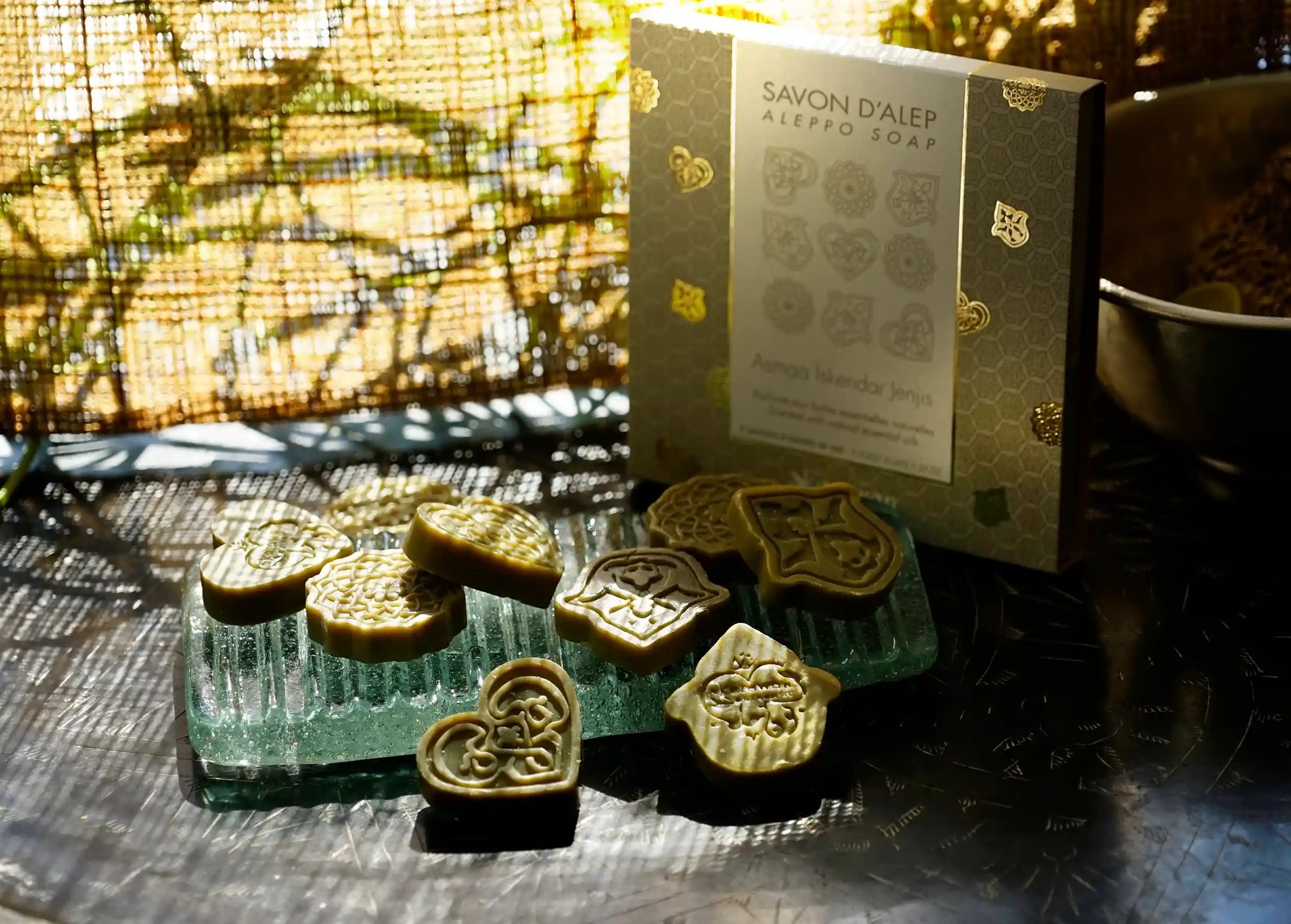 Savons d'Alep d'invités parfumés de petite taille sur un porte savon en verre