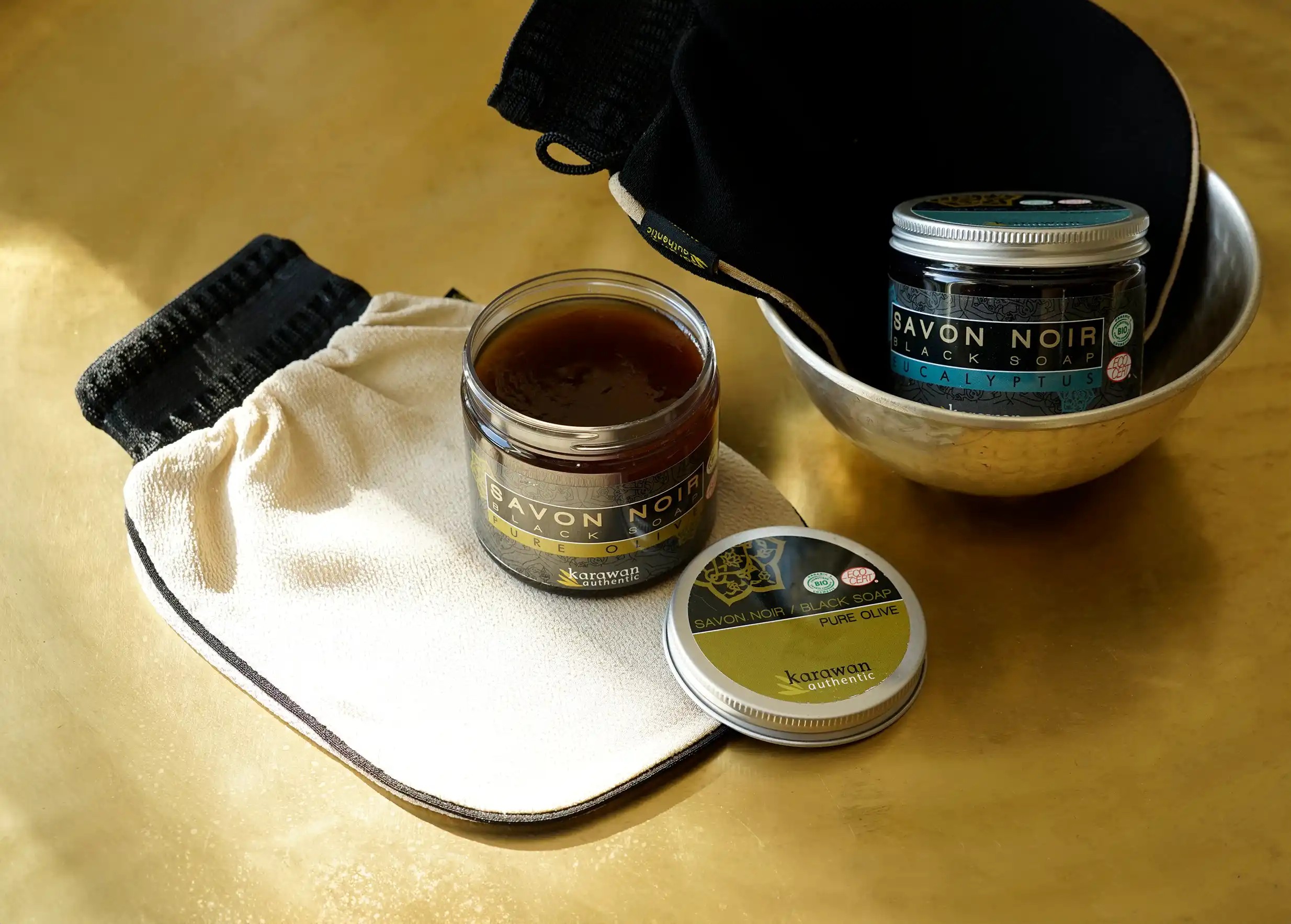 Open jar of pure olive soap, with eucalyptus soap and kessa gloves