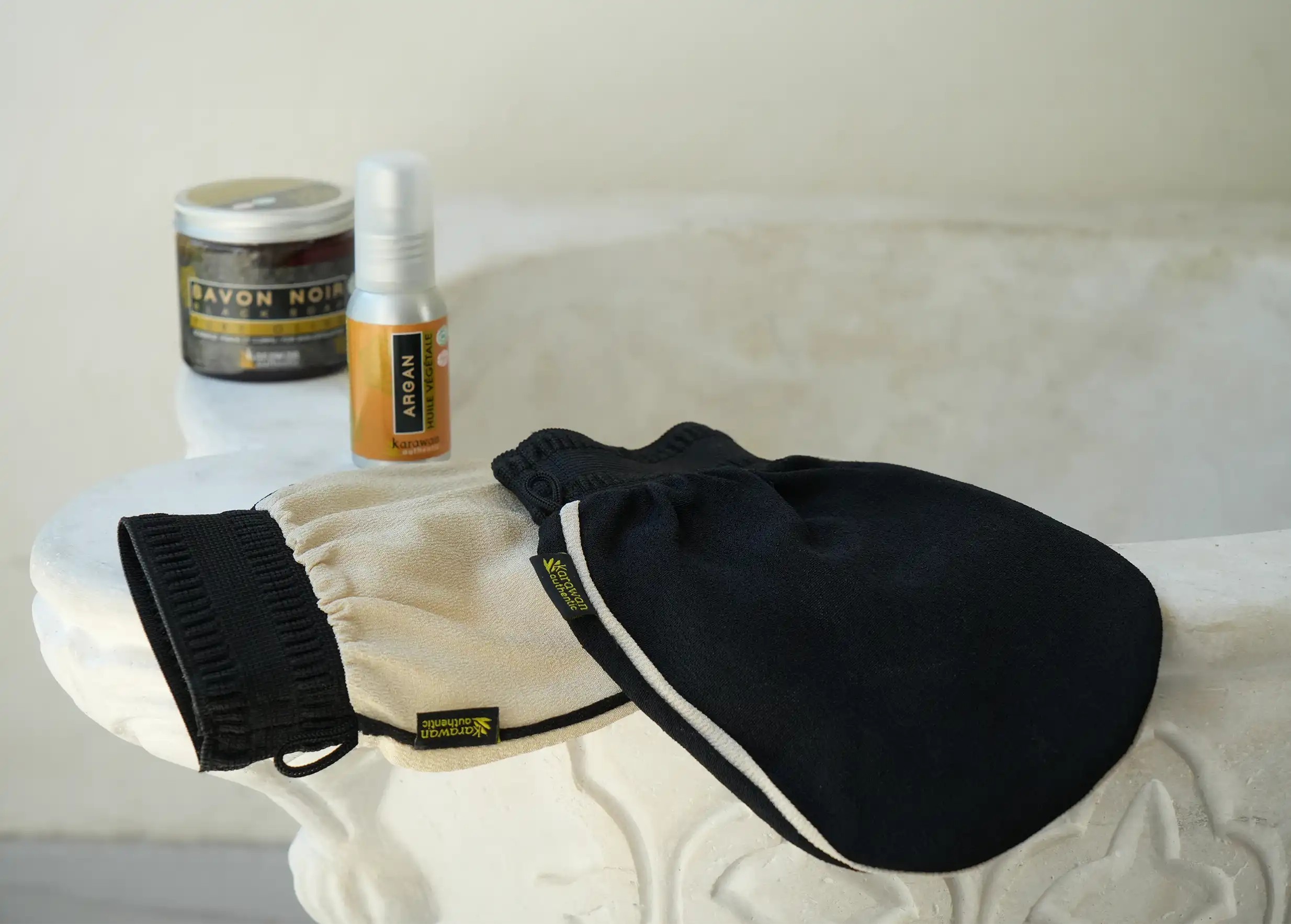 Black and beige kessa gloves, jar of black soap and organic argan oil