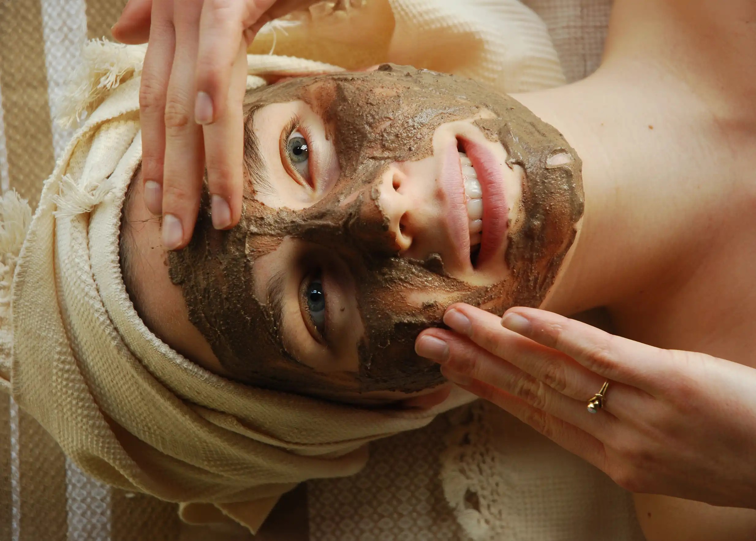 Woman spreading a rhassoul facial mask, hammam atmosphere