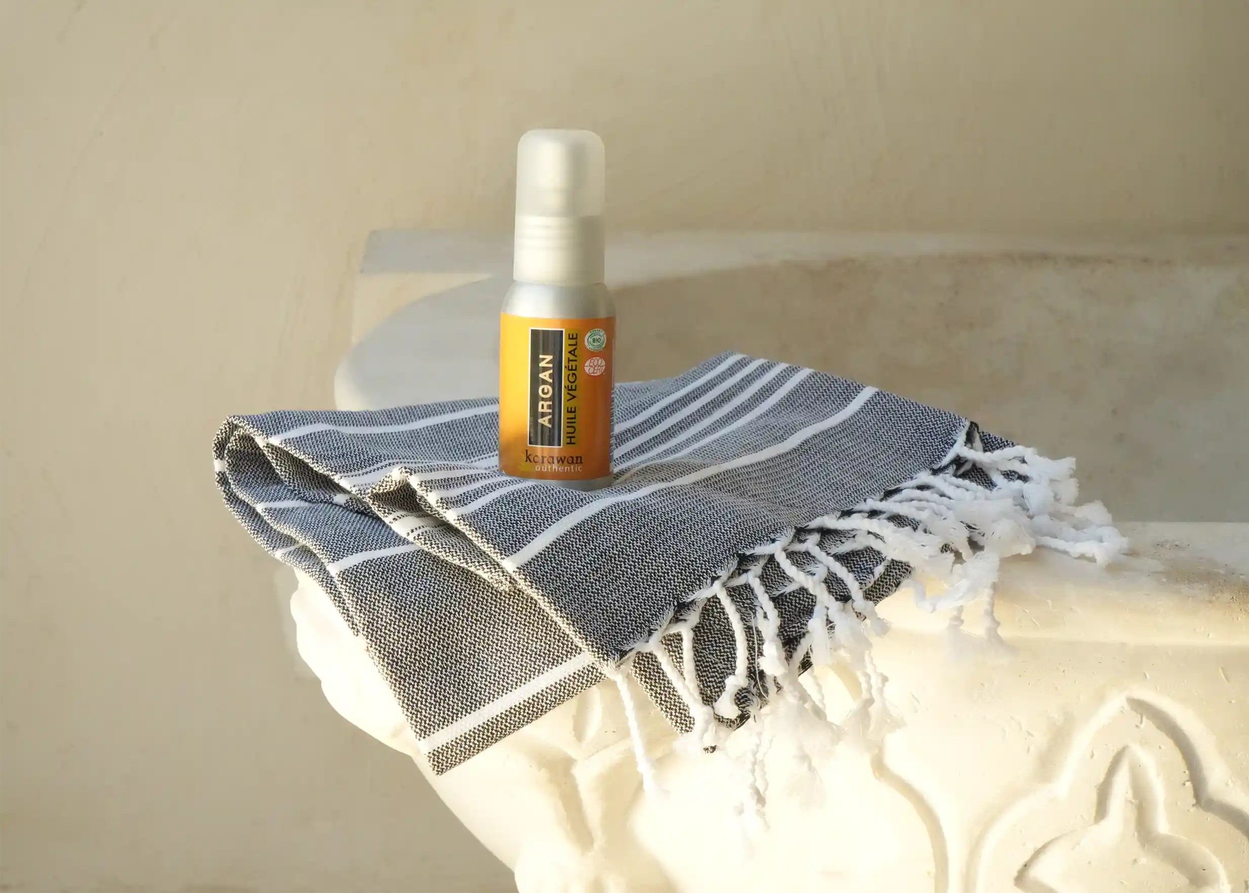 Organic argan oil in a bottle, on a hammam fouta