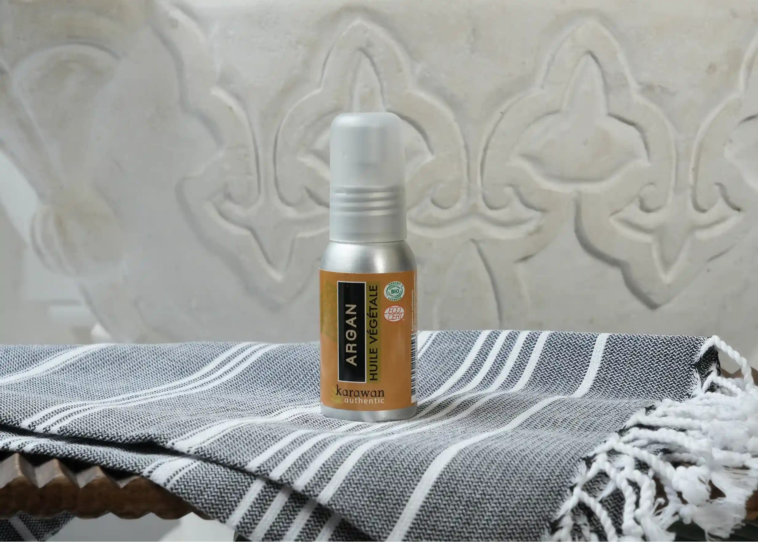 Argan oil certified organic by Ecocert, in a small 50ml bottle, on an organic cotton fouta.