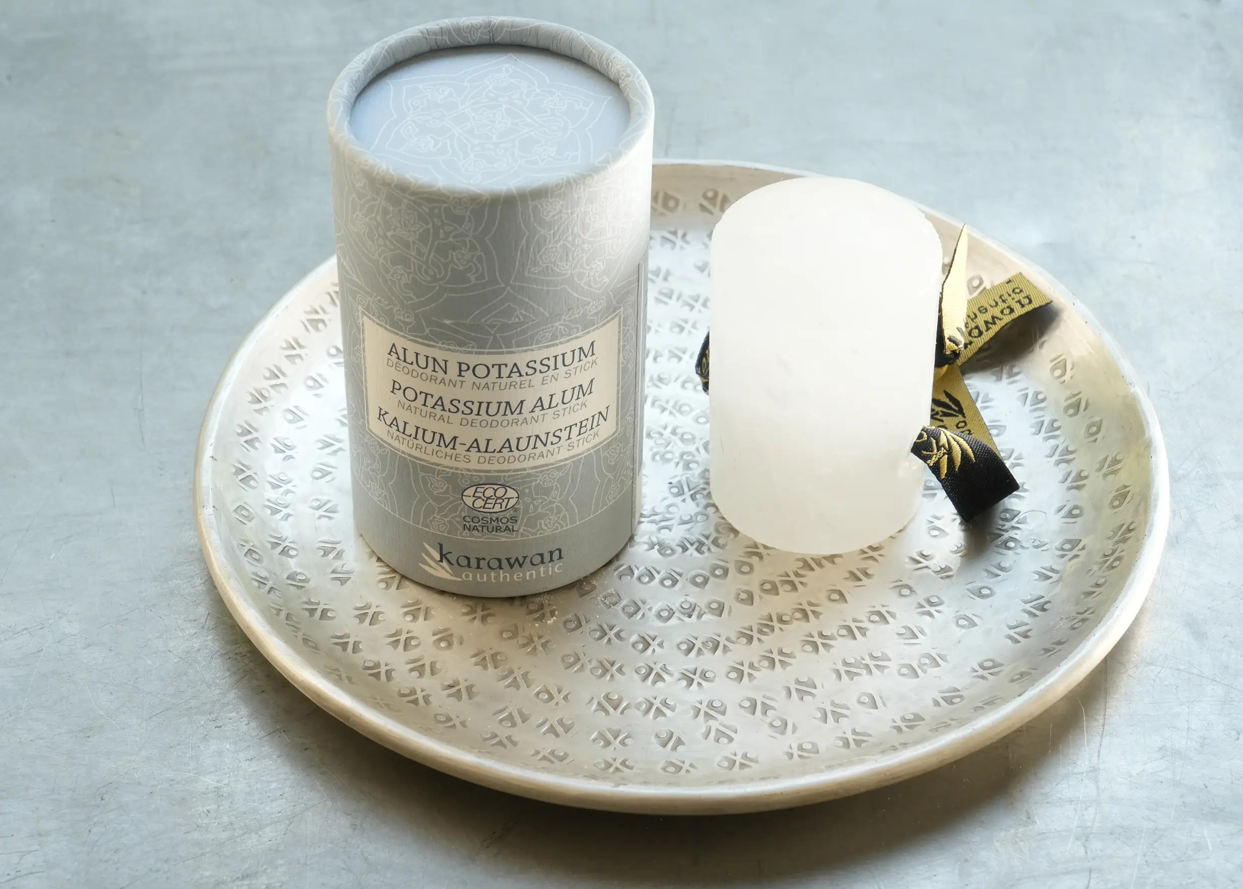 Alum stone stick, Cosmos natural certified, and its packaging on a brass dish