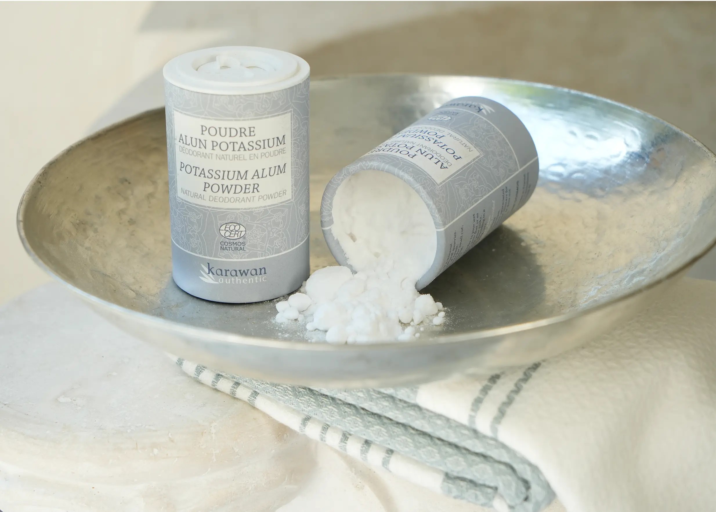 Two tins of potassium alum powder, one upright and one upside down