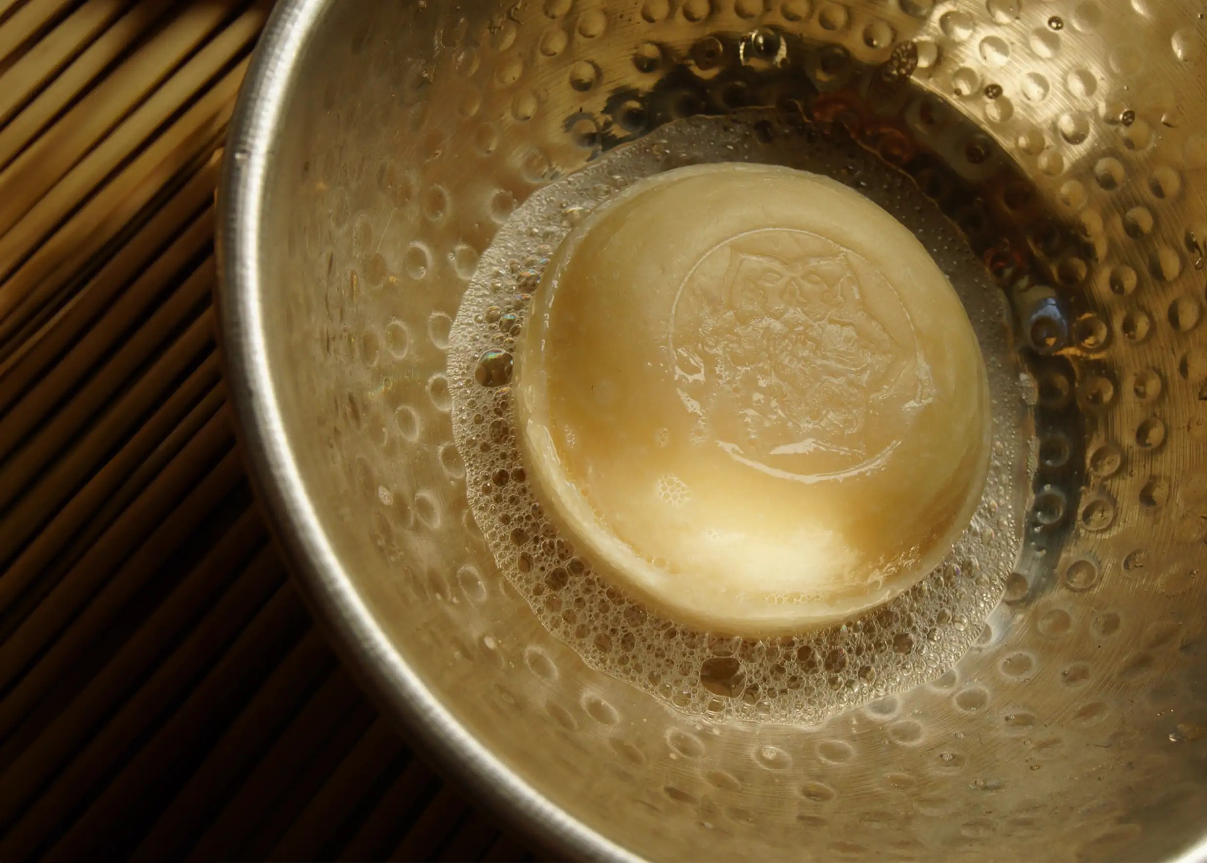 Savon basilic sacré moussant dans un récipient en laiton