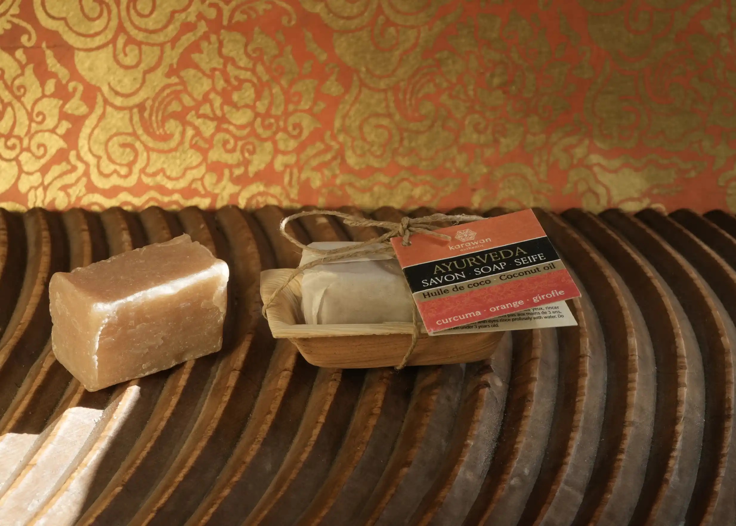 Mini Ayurvedic soaps made with coconut oil, turmeric, orange and clove, placed on a wooden surface.