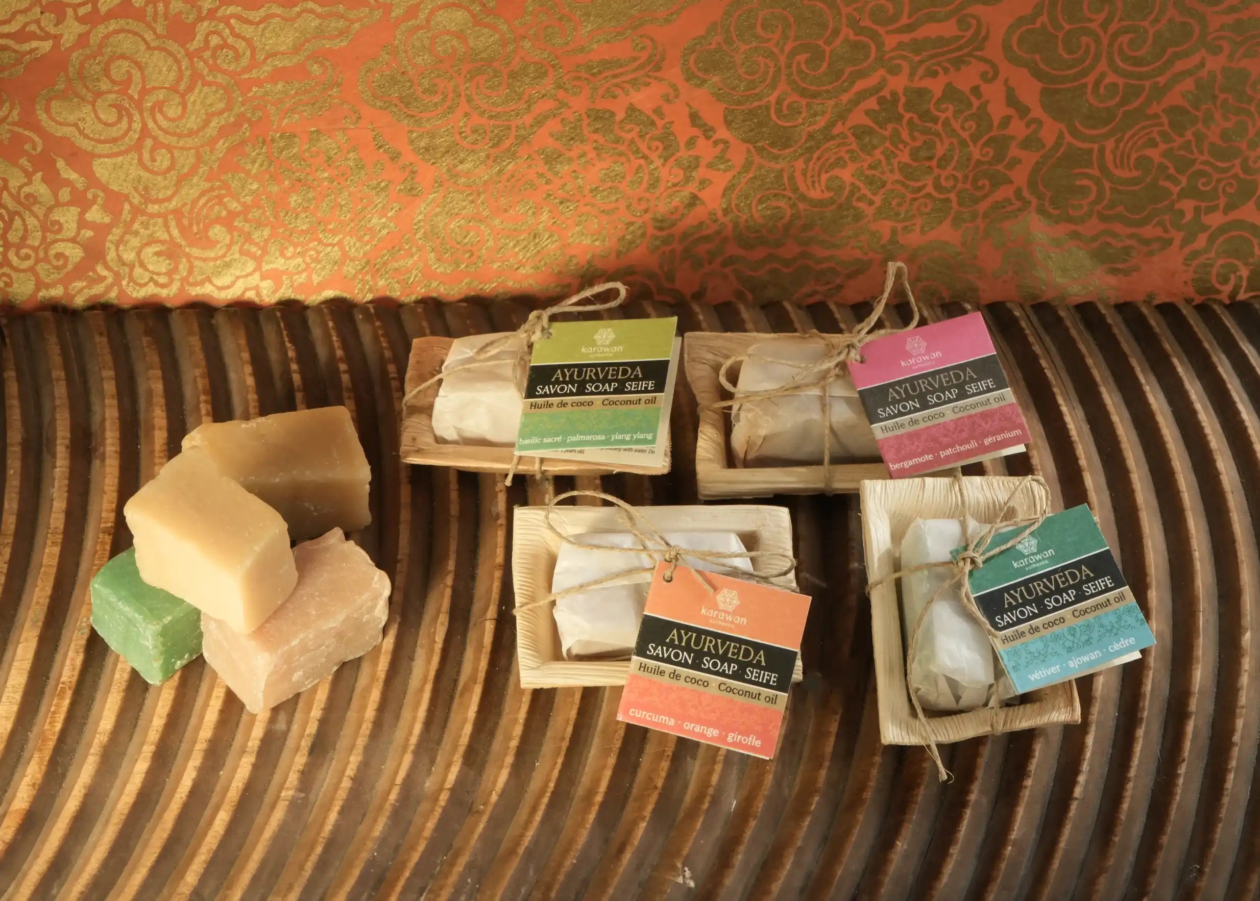 Savons ayurvédiques carrés Karawan emballés dans des récipients naturels avec étiquettes, et pile de mini savons