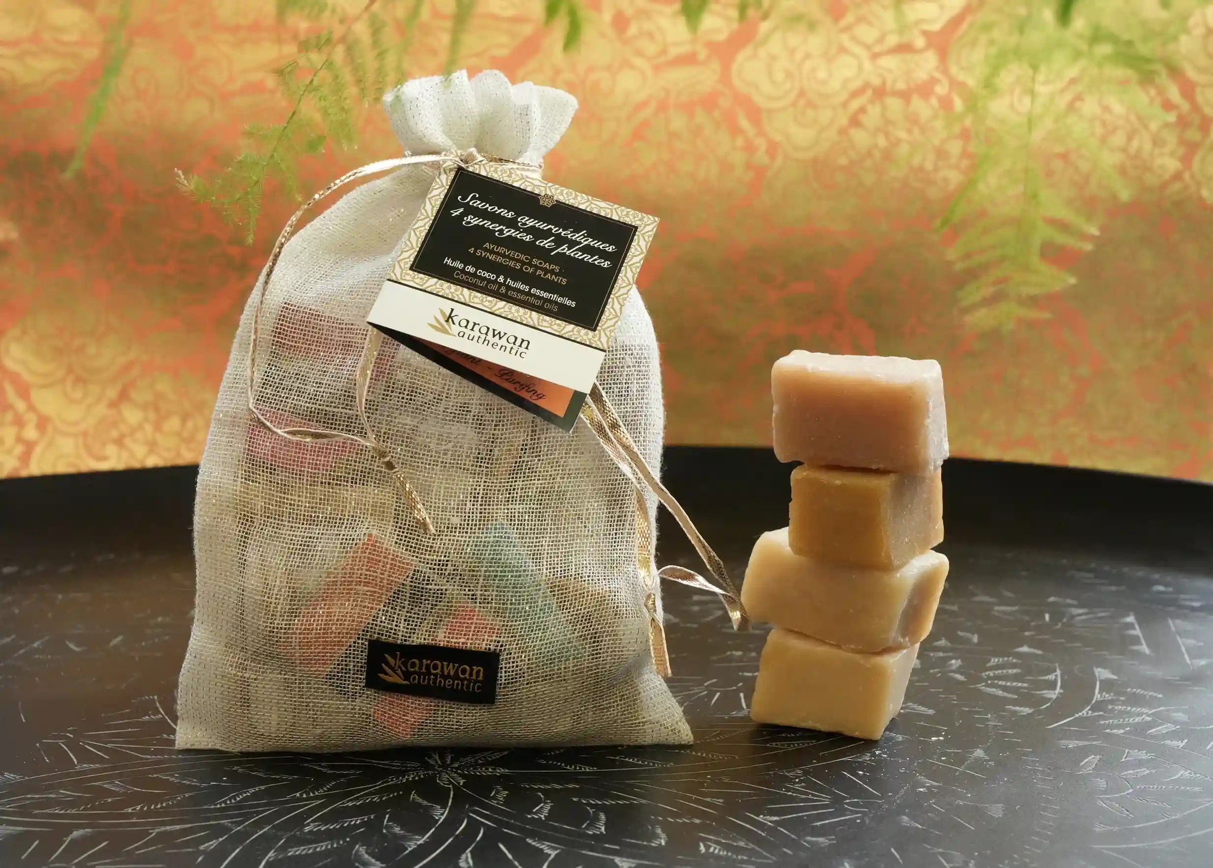 Pouch for ayurvedic soaps, with a stack of unwrapped handmade soaps next to it, on a large engraved brass tray