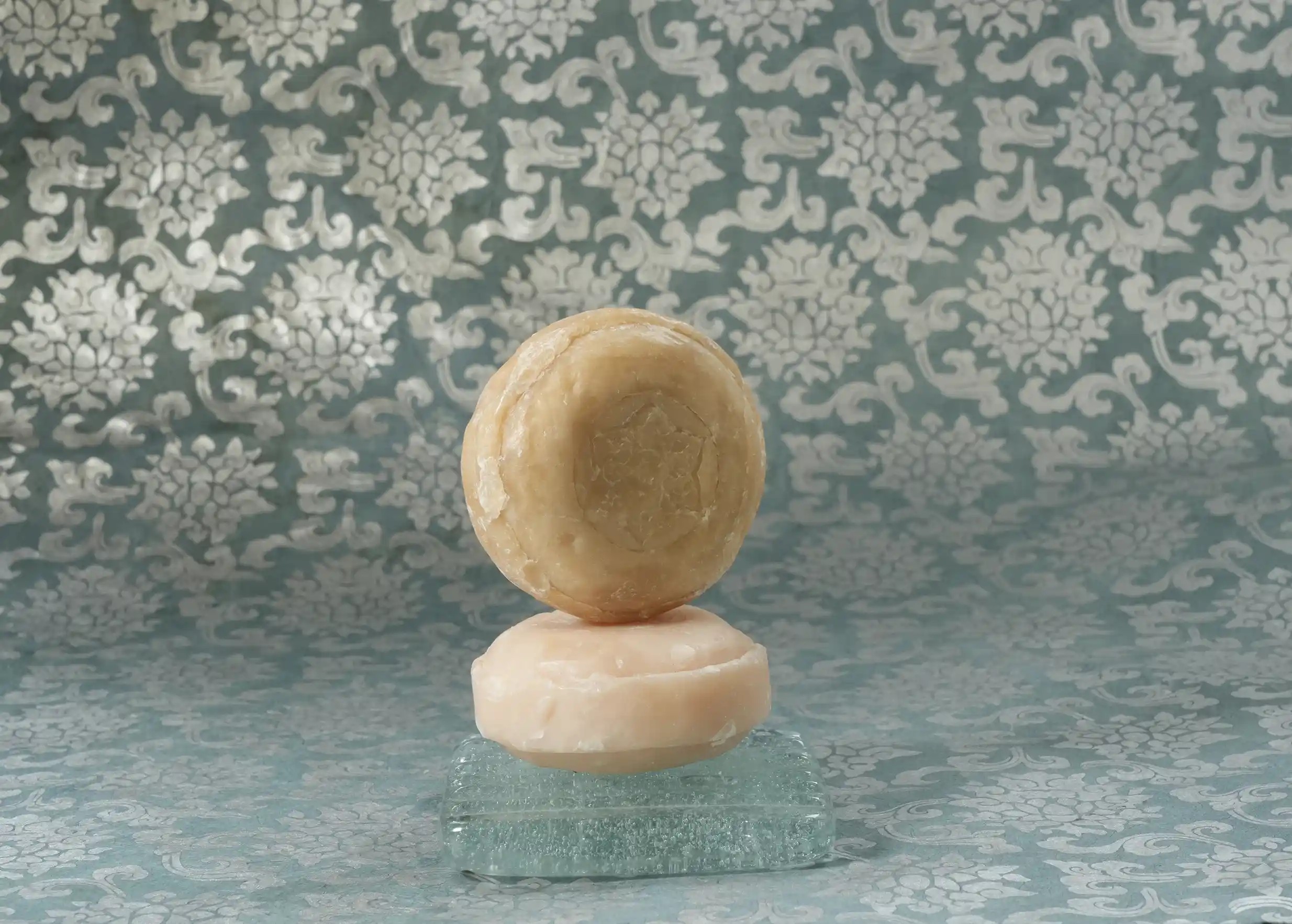 Round ayurvedic soaps with natural ingredients stacked on a soap dish