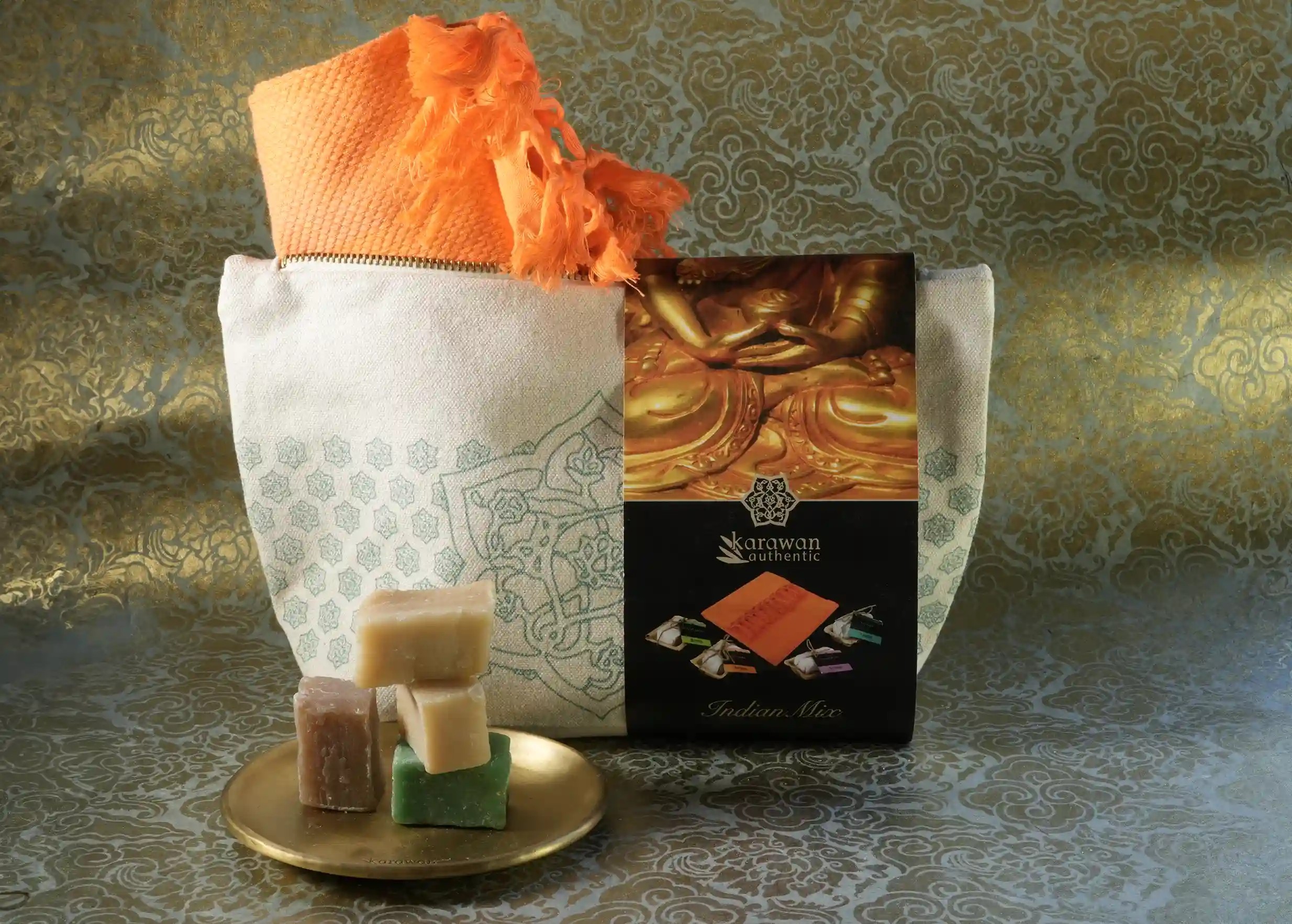 Fouta orange dans une trousse en coton, et 4 petits savons ayurvédiques dans une coupelle en laiton