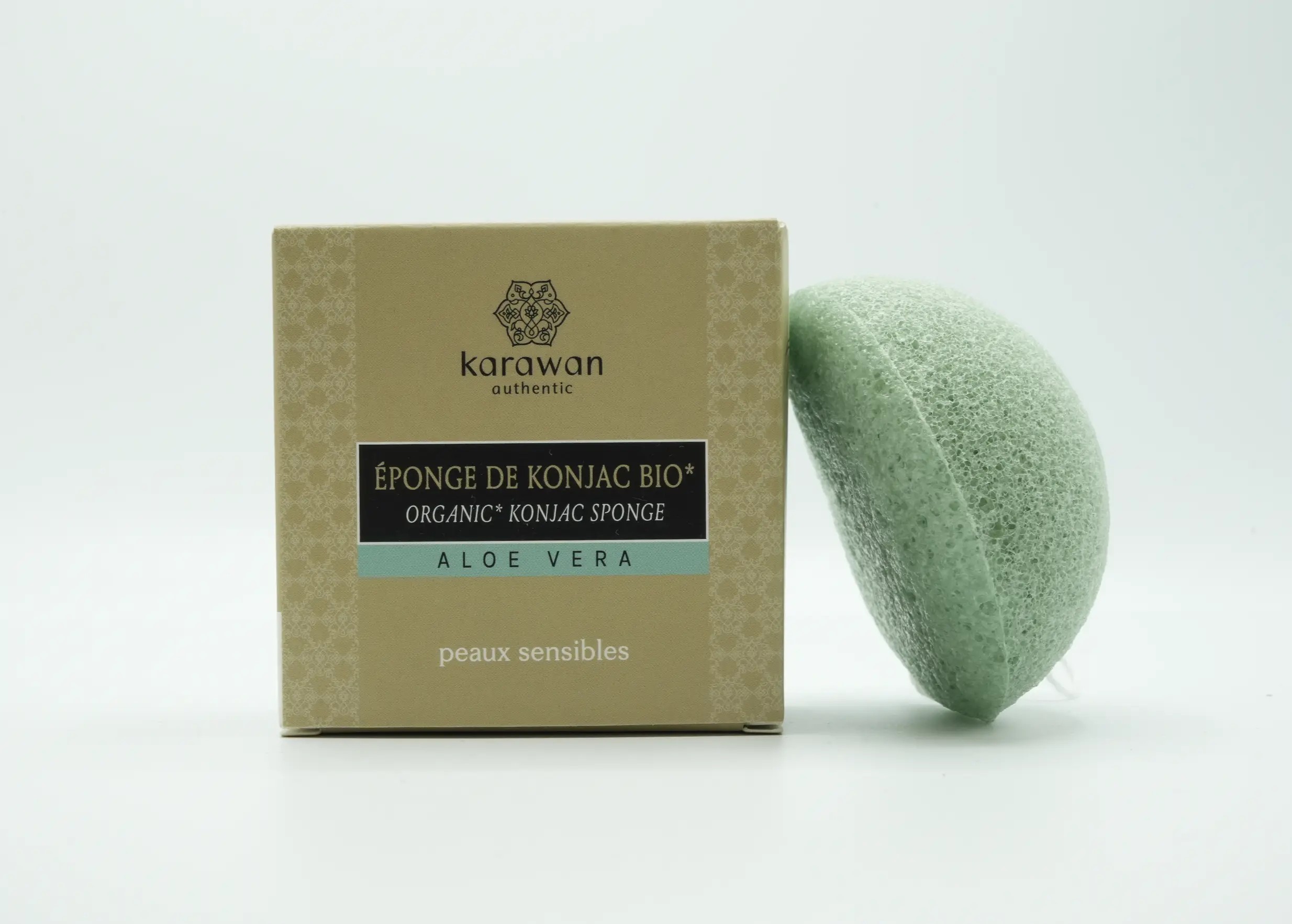 Éponge konjac bio à l'aloe vera, posée contre une boite en carton de la marque Karawan