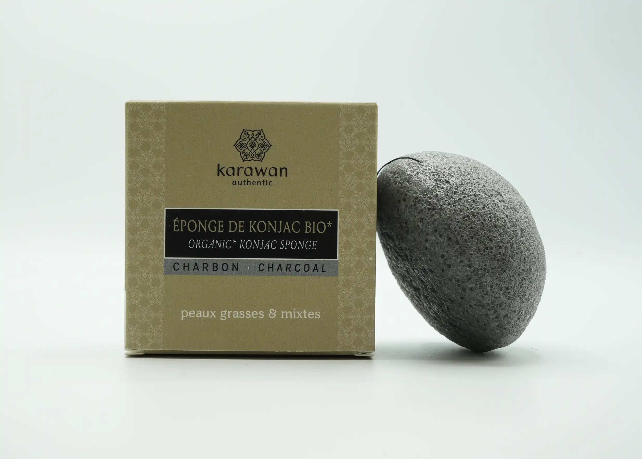 Éponge konjac bio au charbon de bambou, posée contre son packaging en carton, une création Karawan