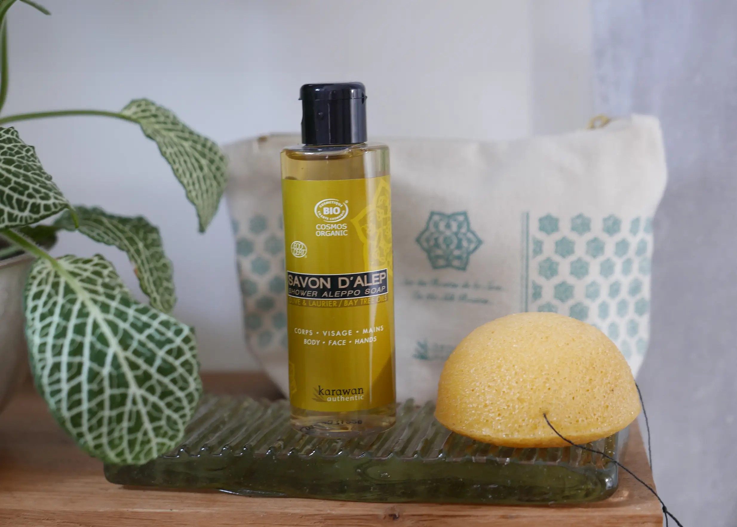 Éponge de konjac bio au curcuma à côté d'un flacon de savon d'Alep bio