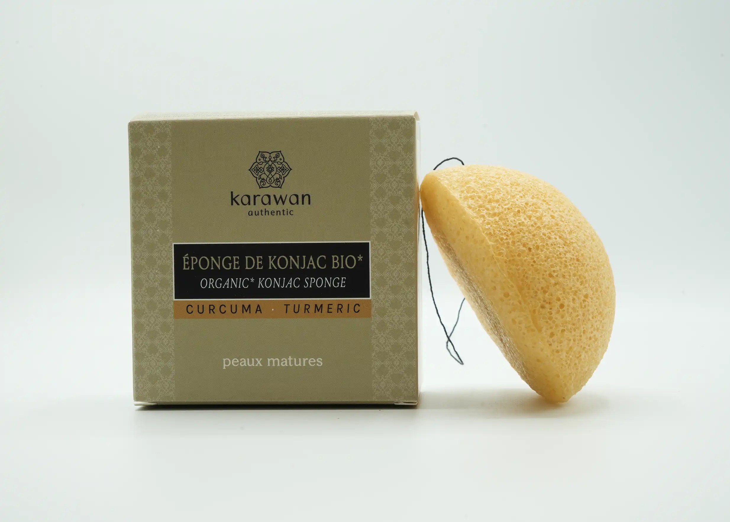 Éponge konjac au curcuma, posée contre une boite en carton de la marque Karawan