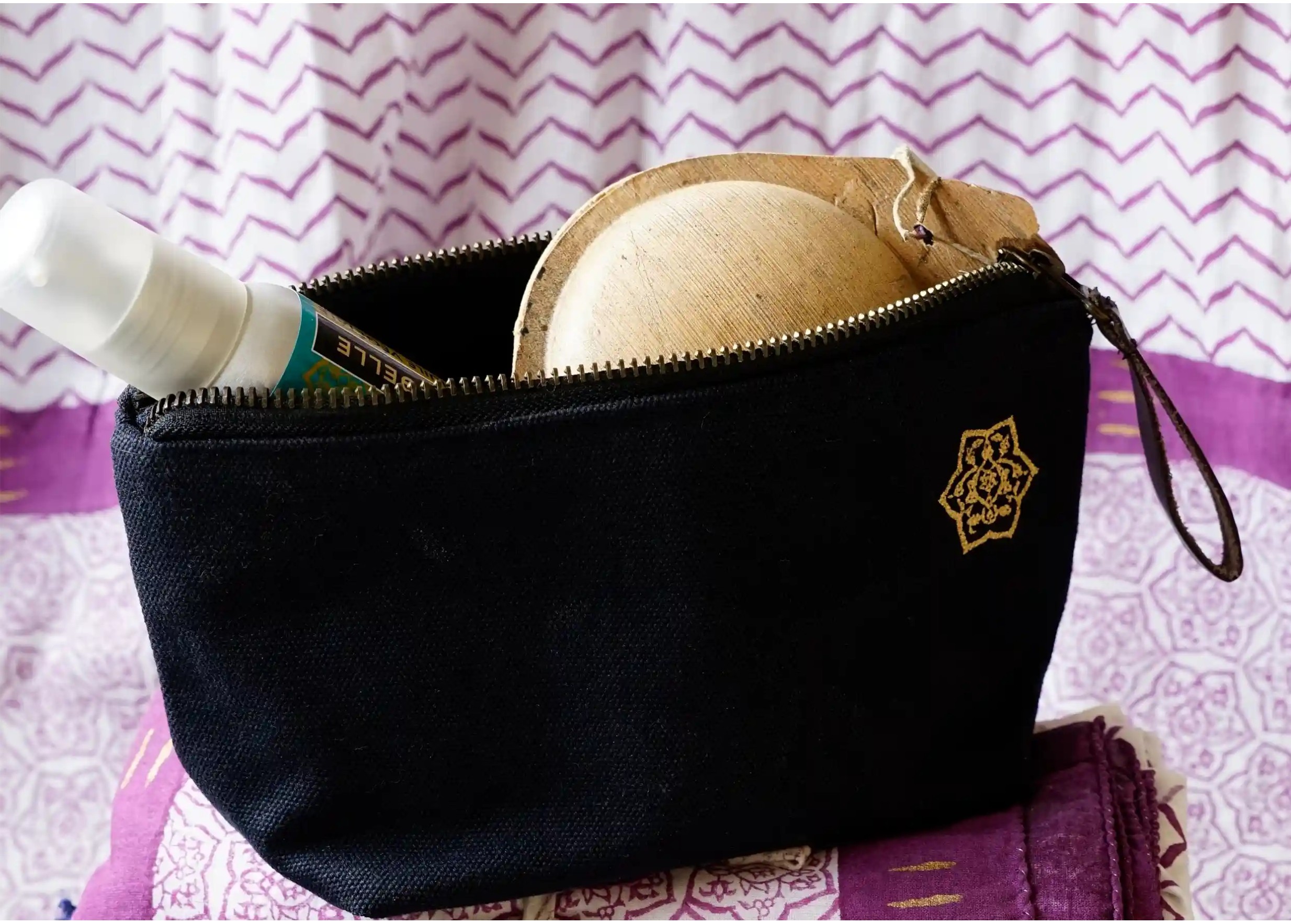 Toiletries bag with zip opening, containing a plant-based care oil and a soap in the shell