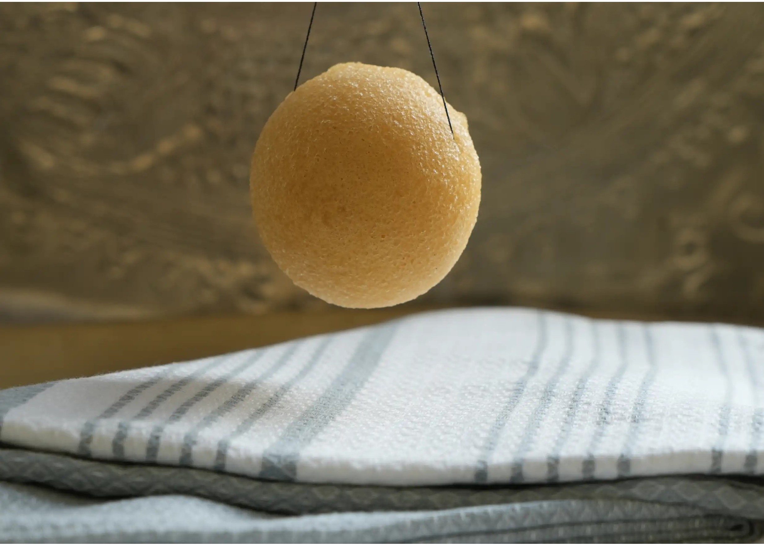 Éponge de konjac enrichie au curcuma suspendue au dessus d'une fouta