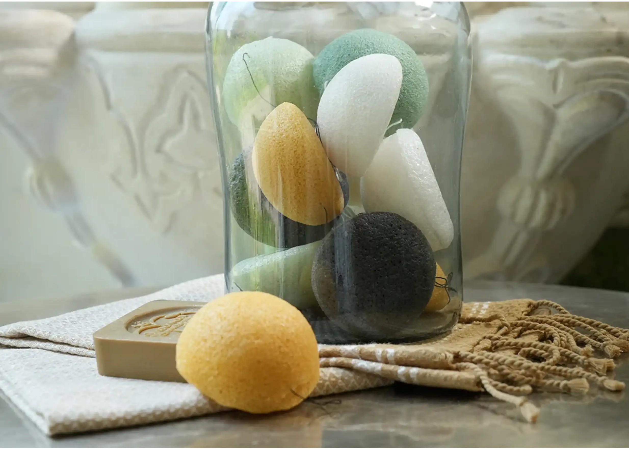 Ensemble d'éponges de konjac de différentes couleurs placées dans un grand bocal en verre transparent