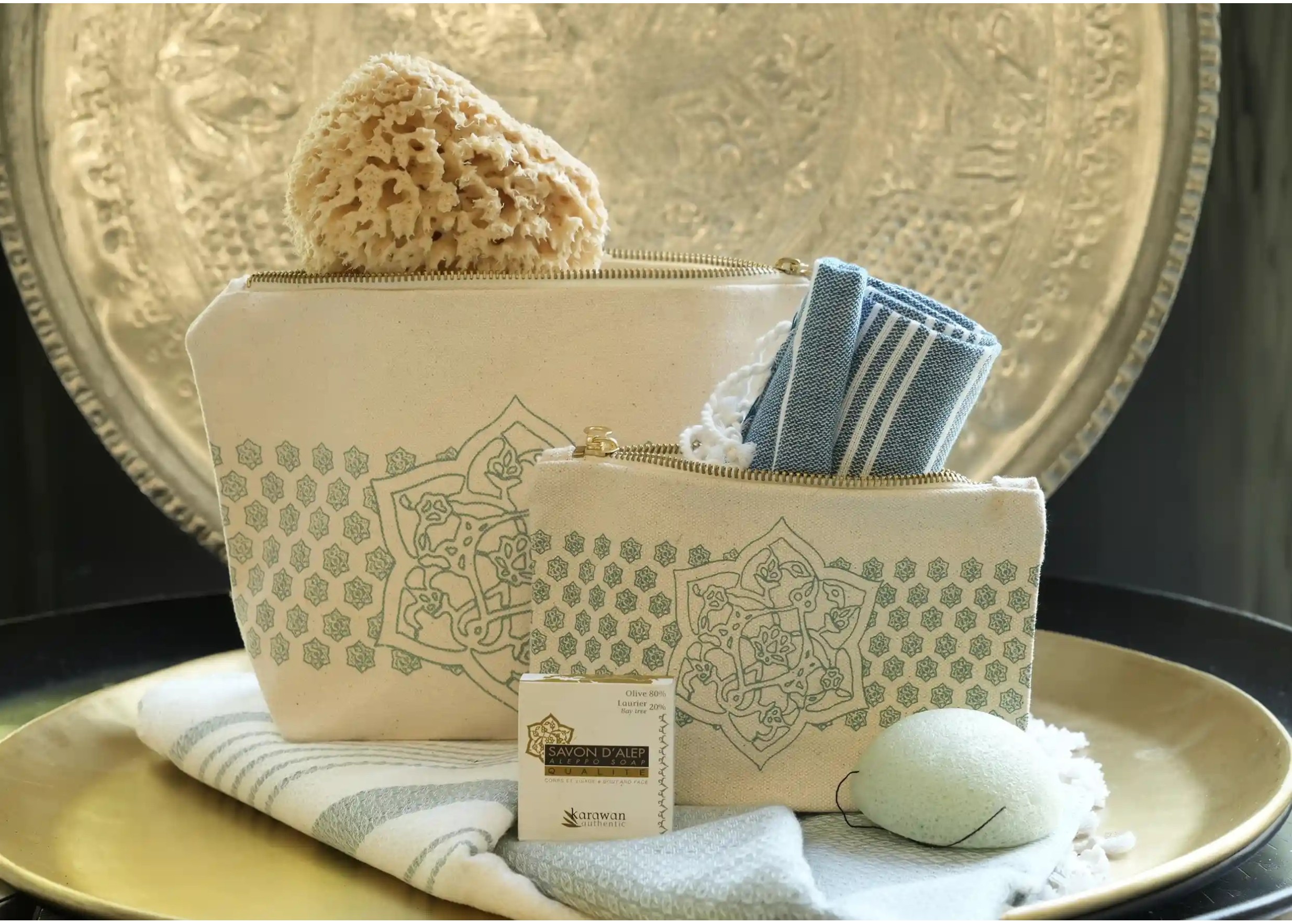 GOTS-certified organic cotton toiletry bags of various sizes, with a fouta, konjac sponge, and natural sponge