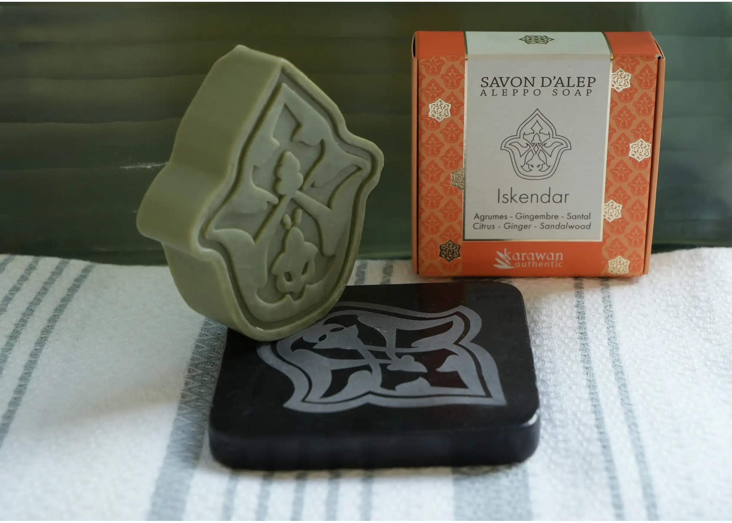 Savon posé debout sur un porte-savon noir en marbre, gravé à la main, fouta et coffret de savon d'Alep doré