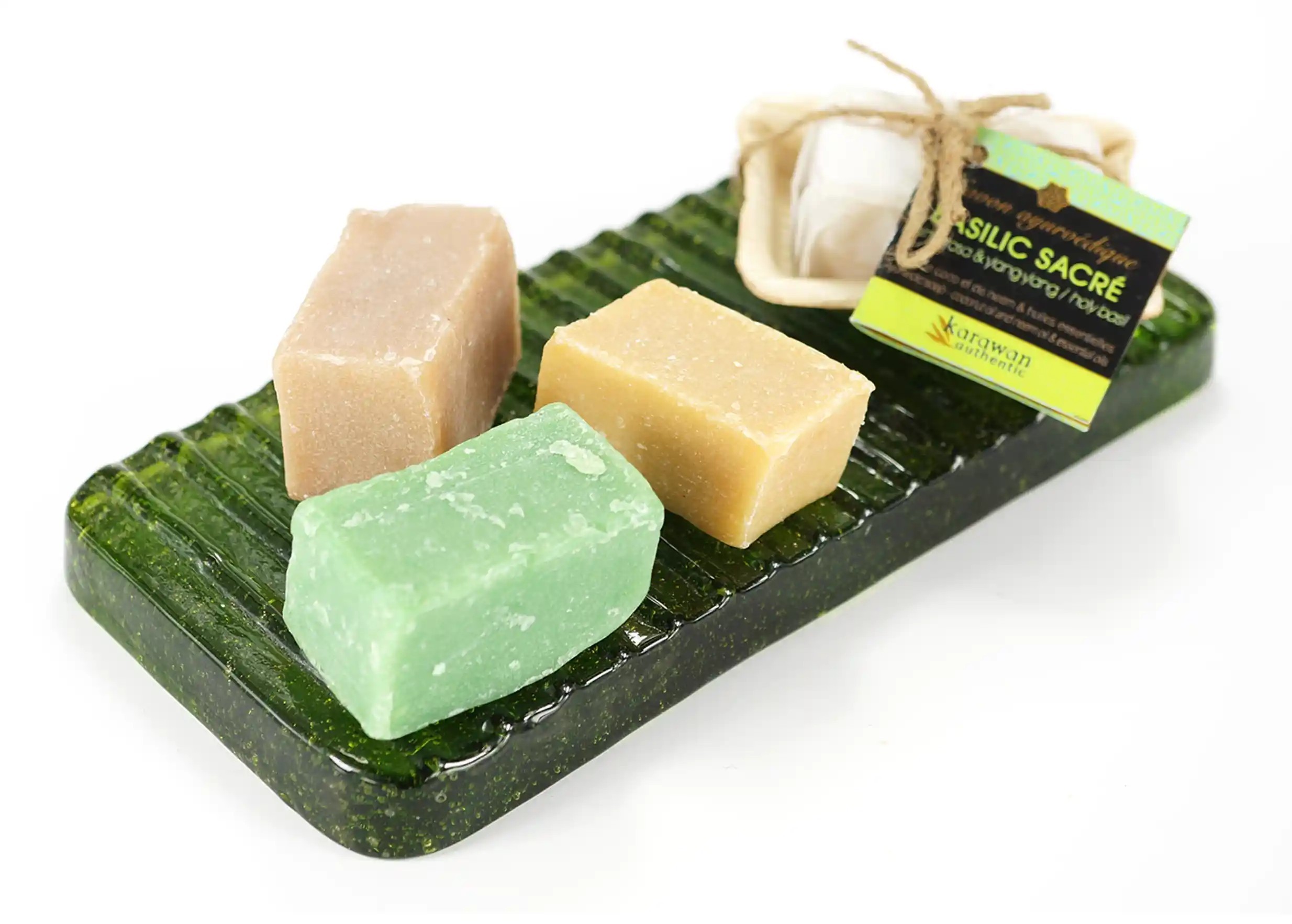 Ice recycled glass soap dish with several ayurvedic soaps on a white background
