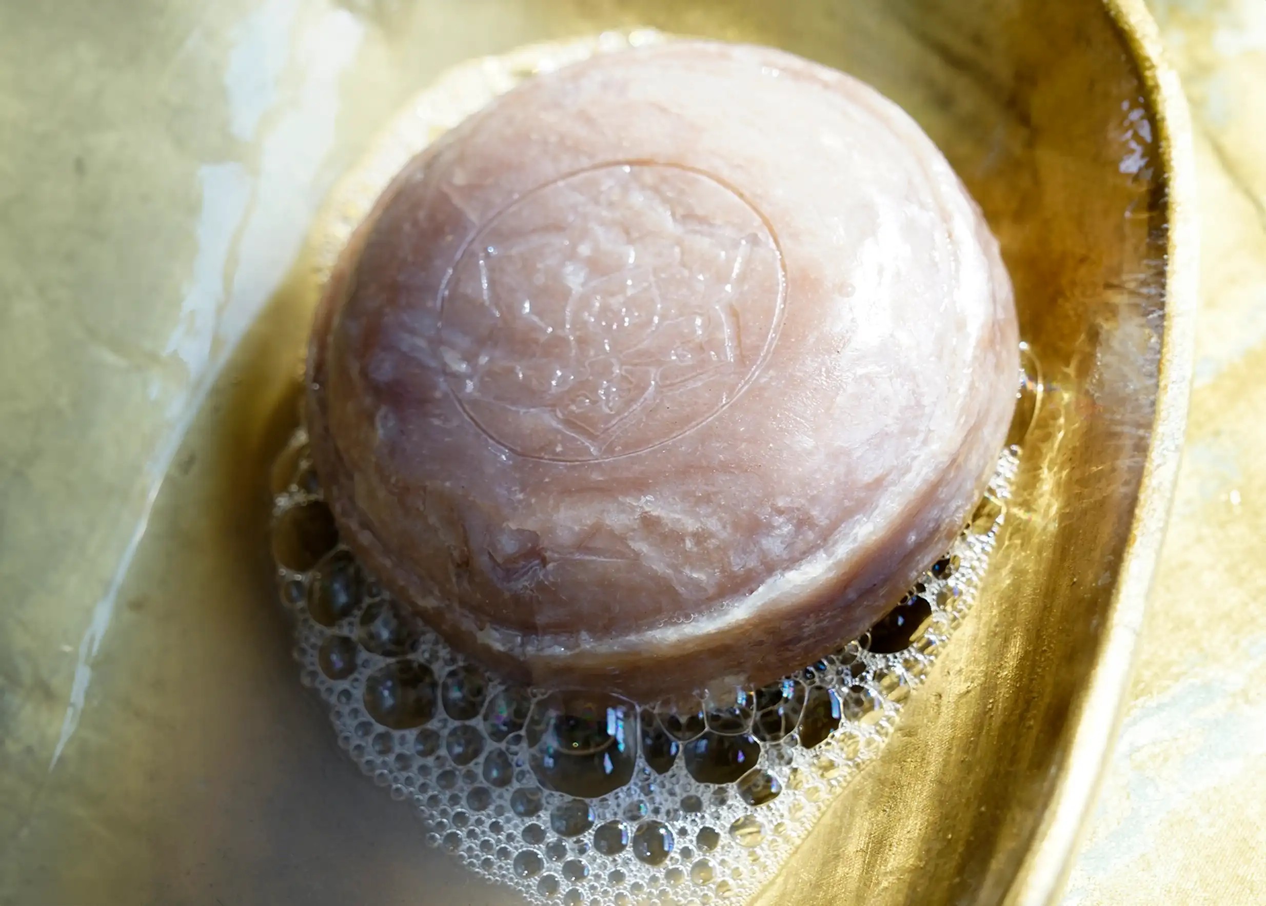 Artisanal ayurvedic soap with bergamot and soap bubbles, presented in a golden container