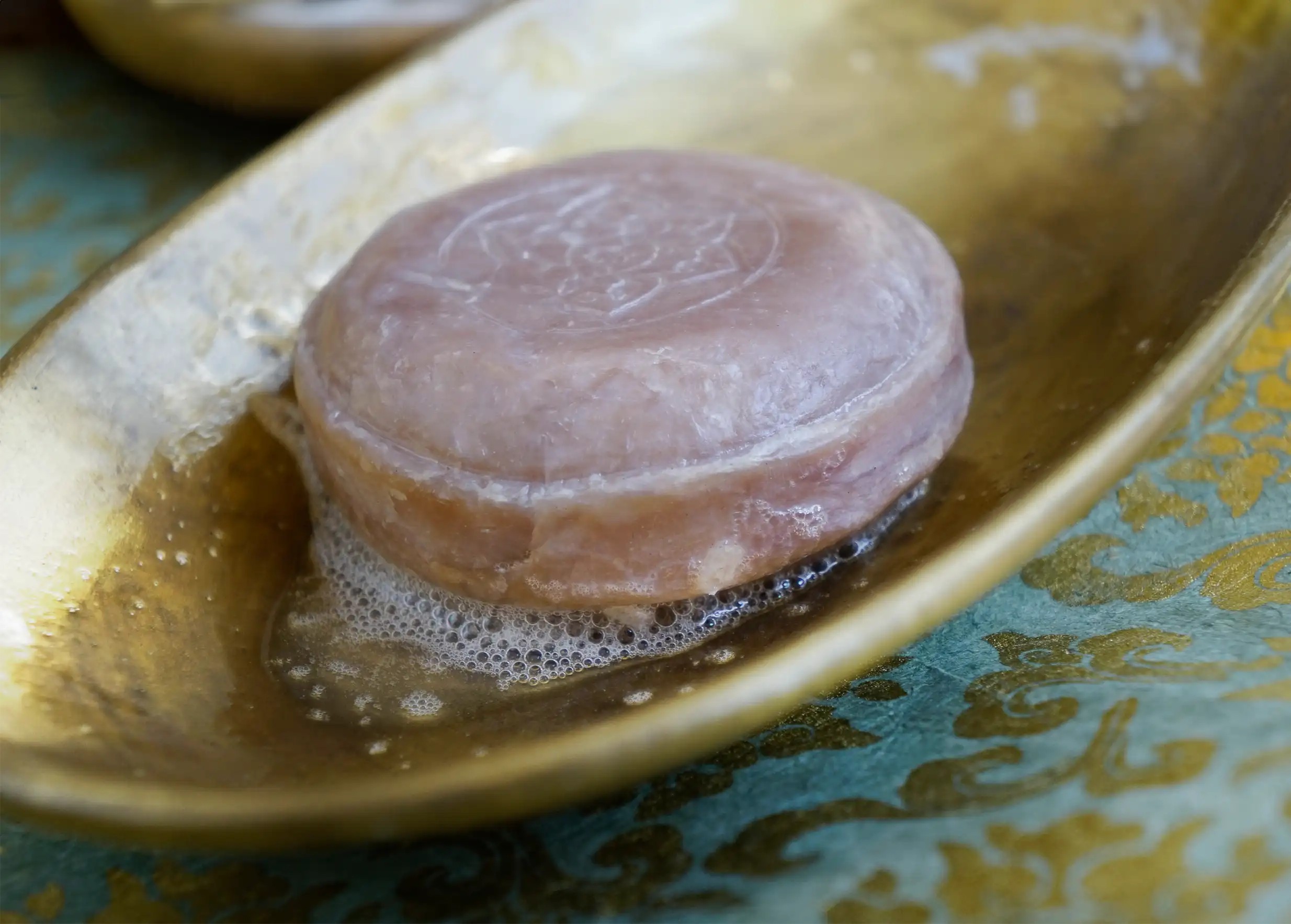 Round, lightly foaming ayurvedic turmeric soap in a golden brass dish