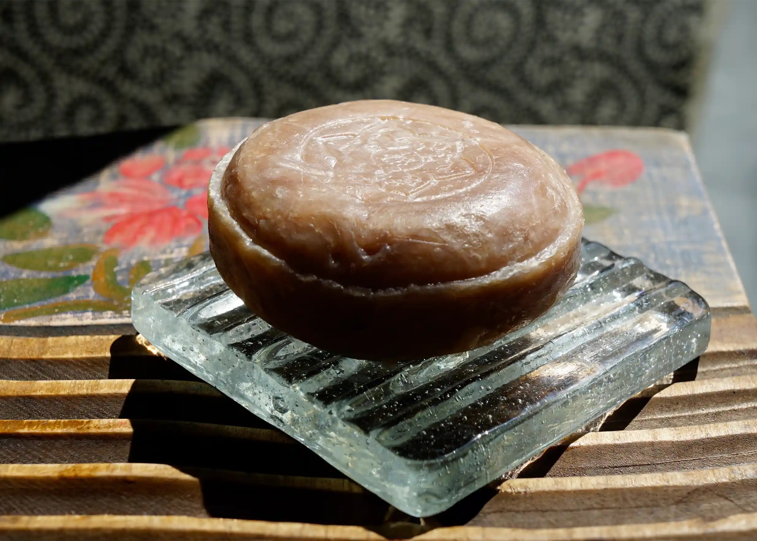 Round solid soap scented with turmeric on a glass soap dish by Karawan
