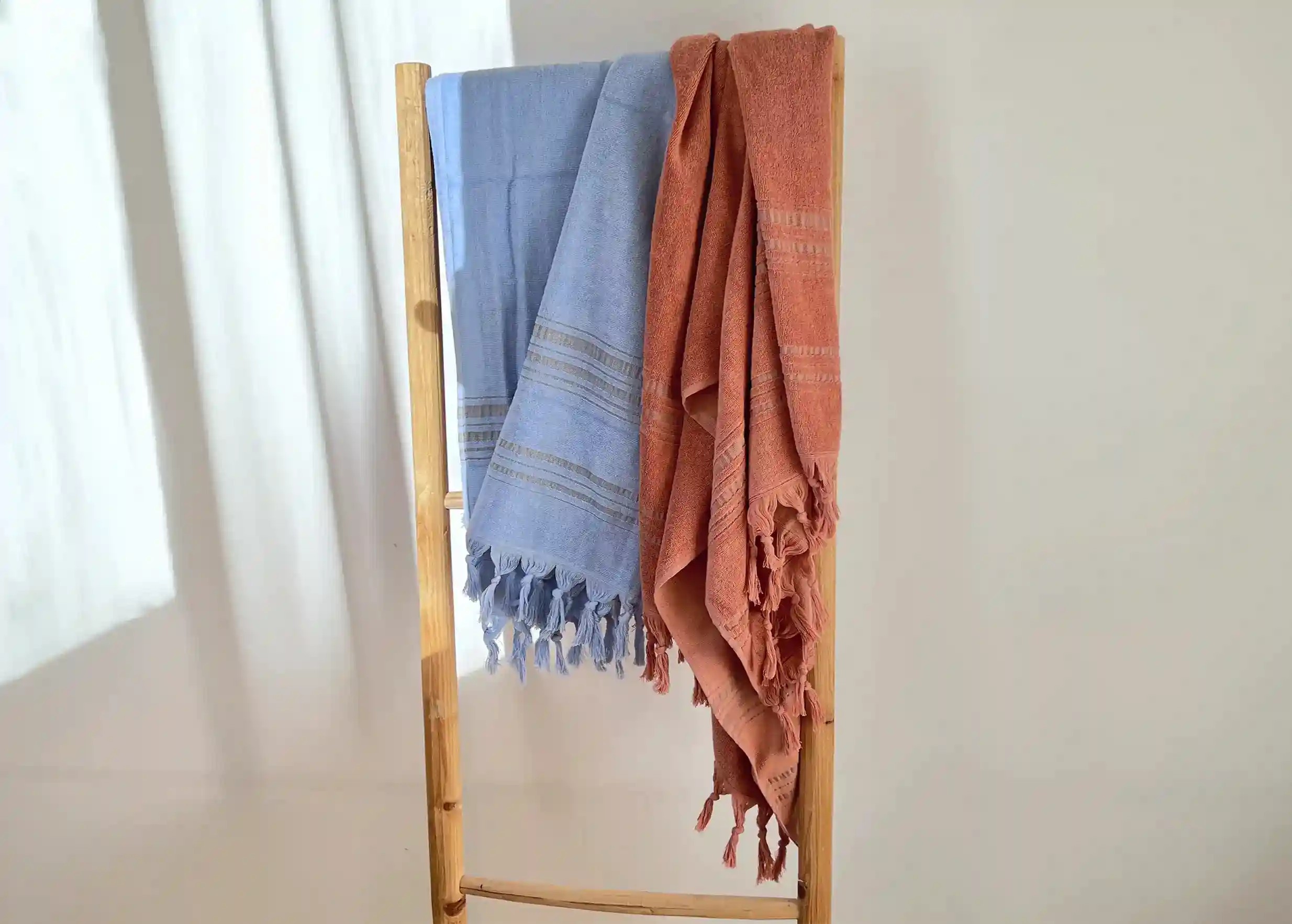 Dolce fouta en coton bio Azurine, avec fouta couleur ambre, suspendues à un porte-serviette en bois