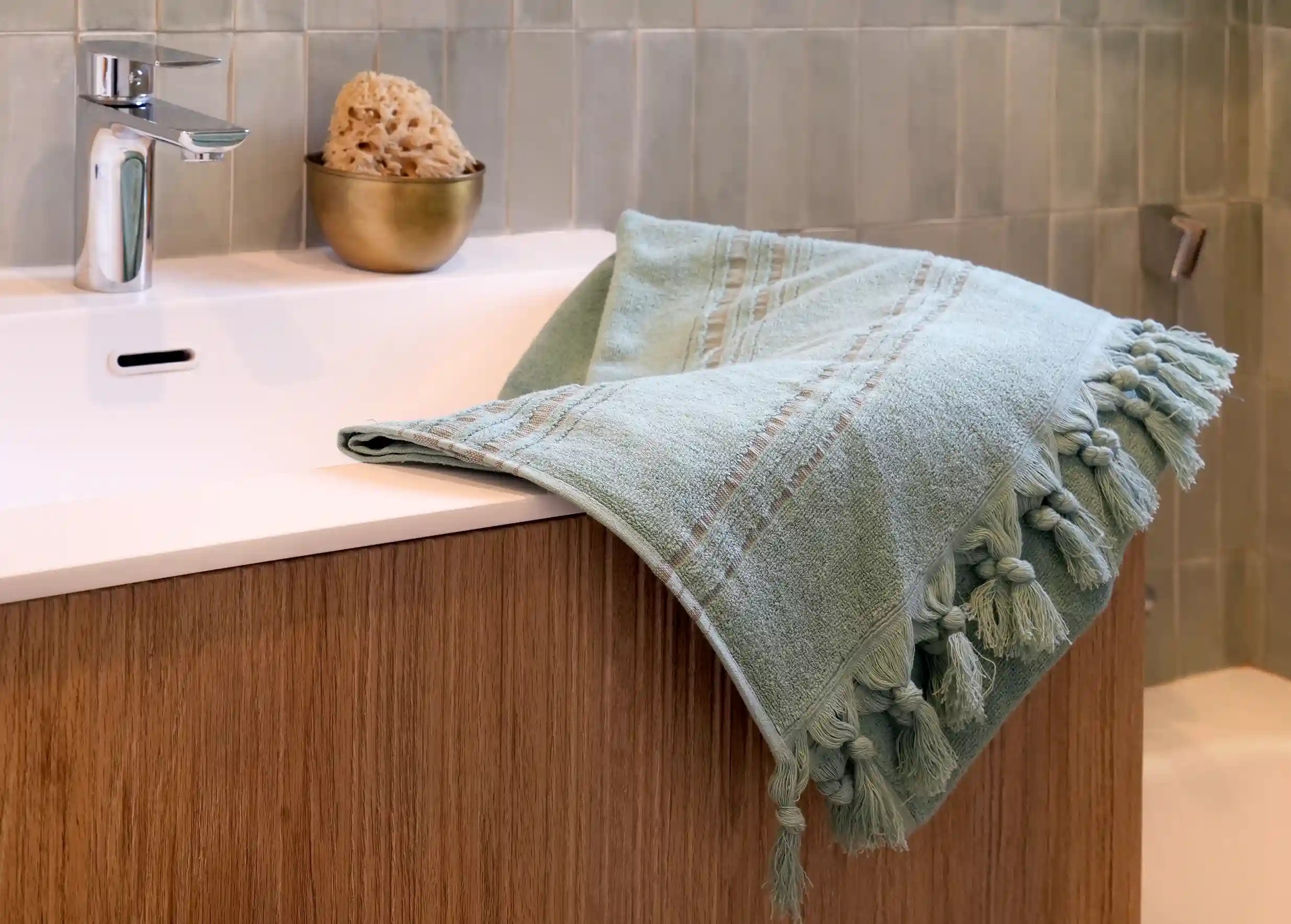 Fouta rayée de la collection Dolce fouta, coloris jade, posée dans une salle de bain