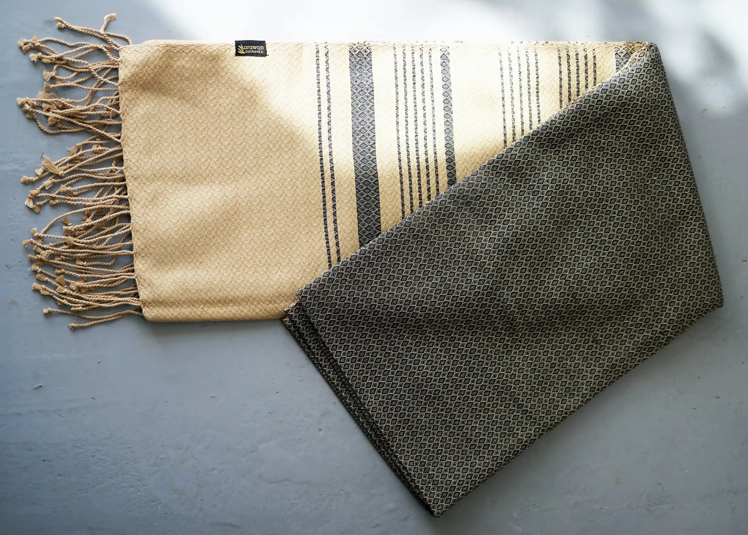 Fouta en coton biologique Sand, coloris cendre, par Karawan authentic, légèrement repliée, des tons foncés et sableux