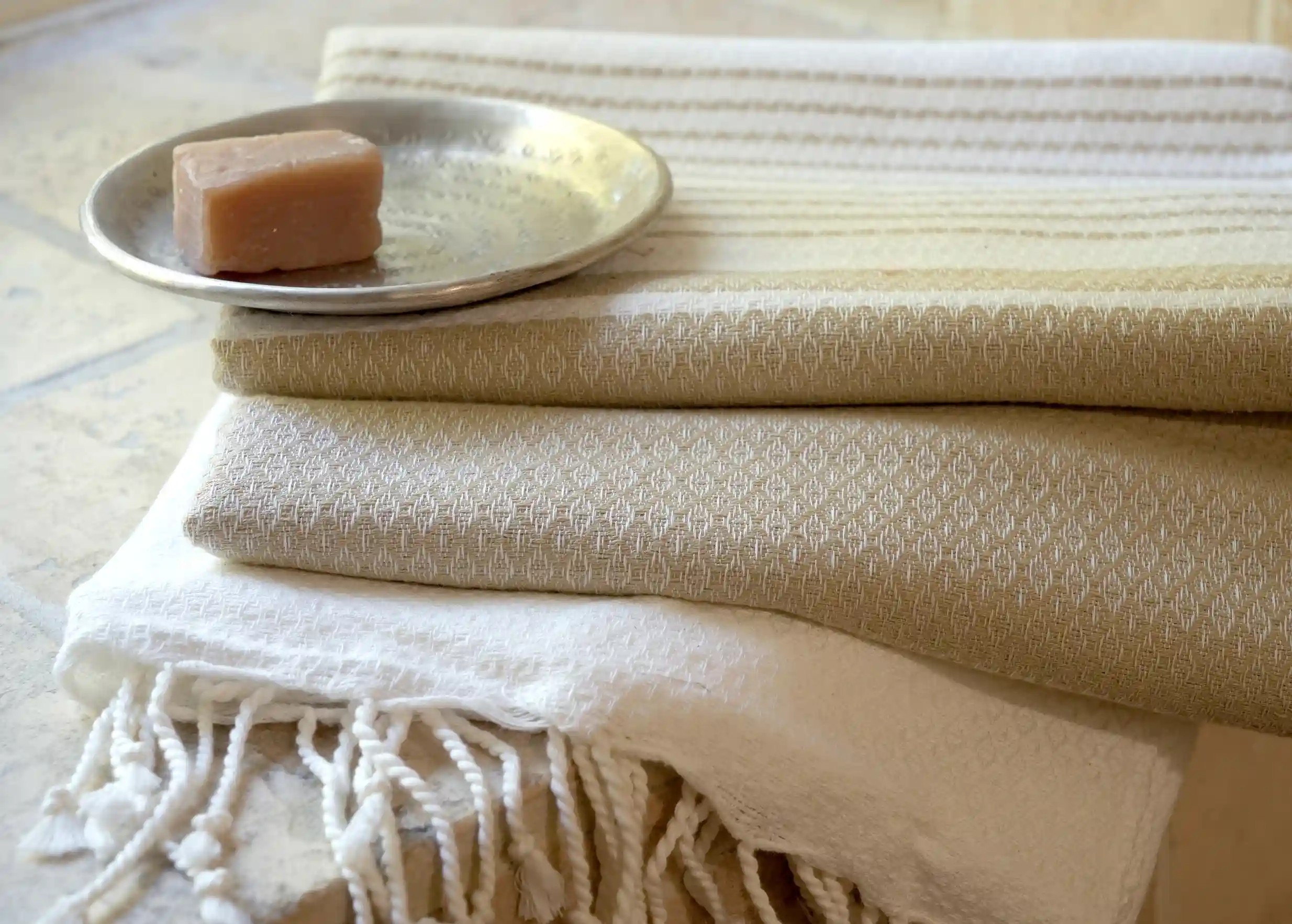 Fouta en coton biologique coloris Ginger, aux franges blanches, posée sur un meuble