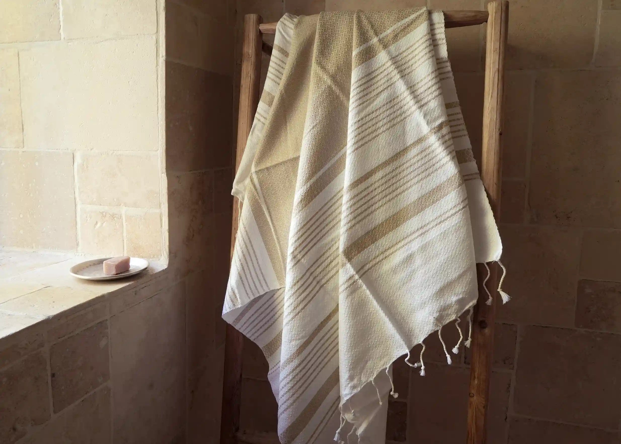 Fouta coloris Ginger, de la collection White Sand par Karawan, sur un porte serviettes en bois