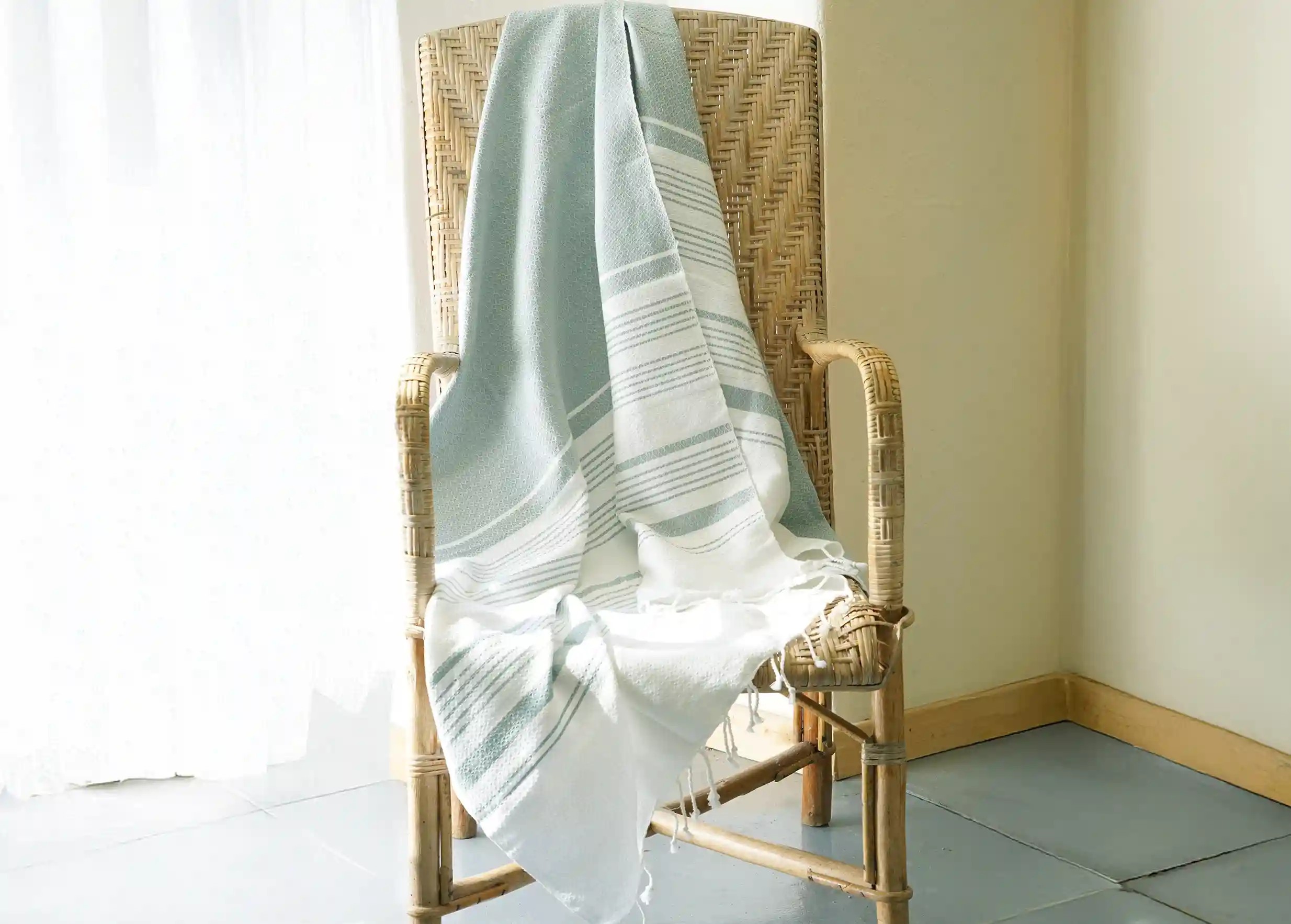 Mirage-coloured fouta in cotton, grey and white stripes, on a chair