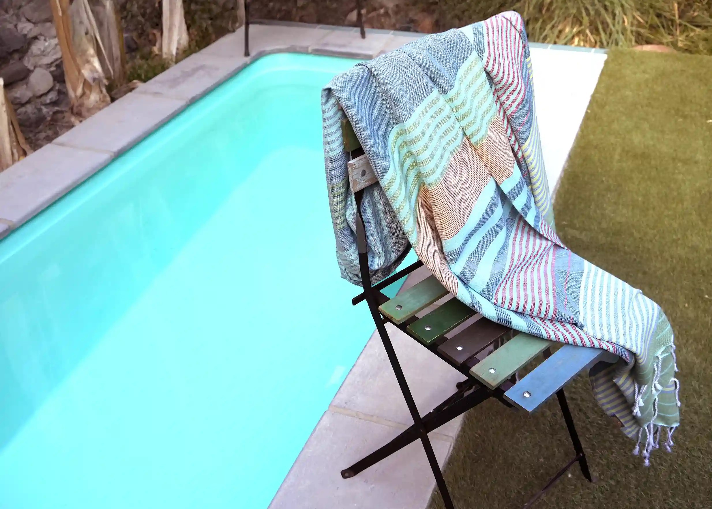 Fouta en coton biologique coloris Adriatic sur une chaise, près d'une piscine