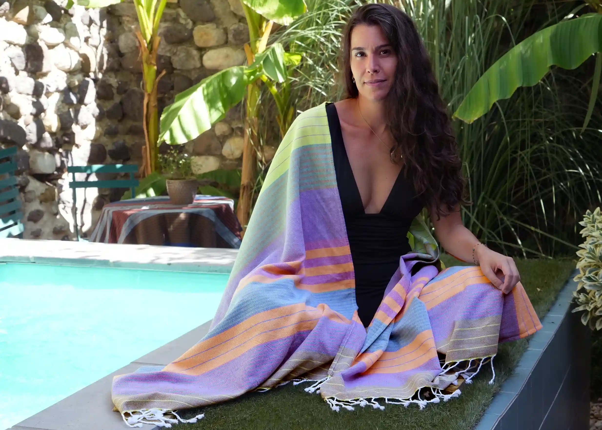 Purple sun coloured organic cotton fouta worn by a woman near a swimming pool