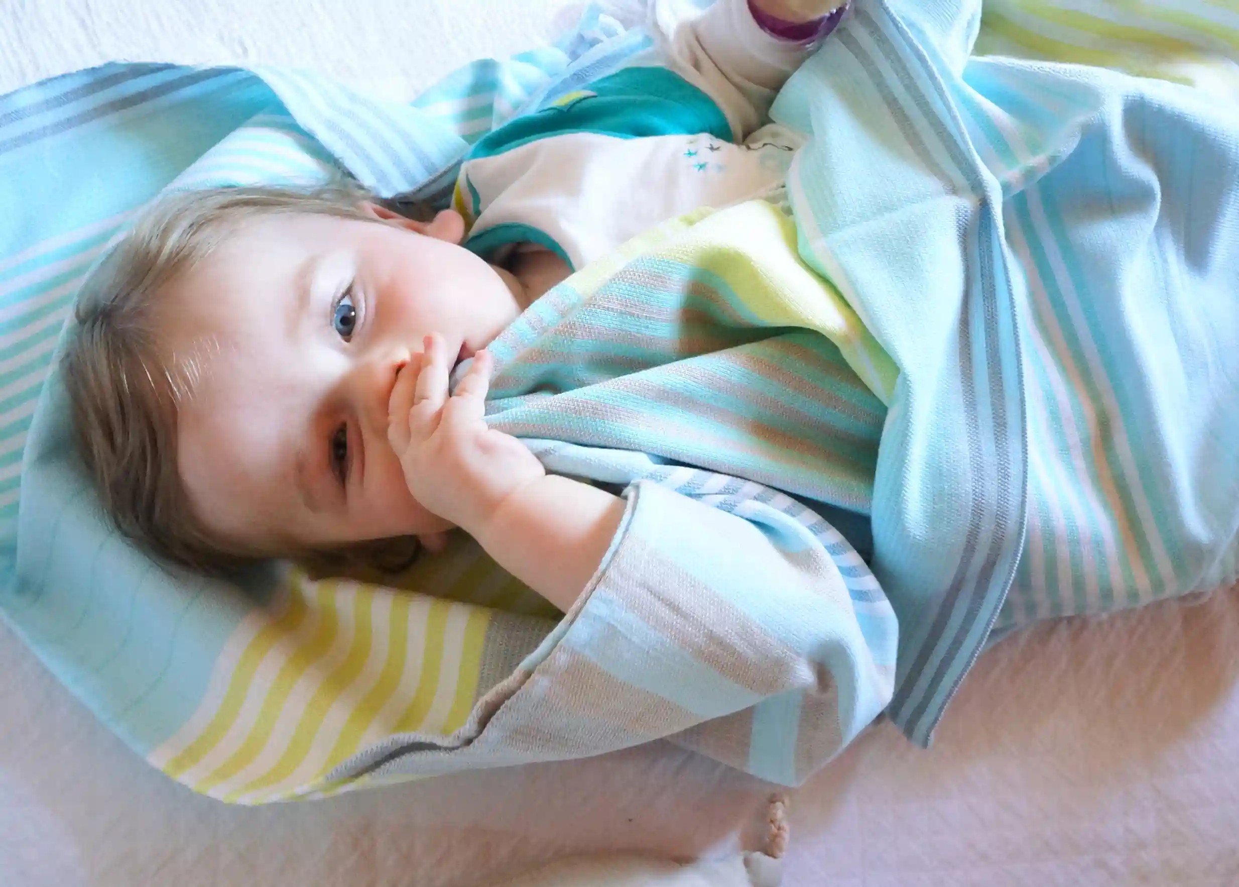 Sunny Lime coloured cotton fouta, wrapped around a child, with hand-tied white stripes and fringes